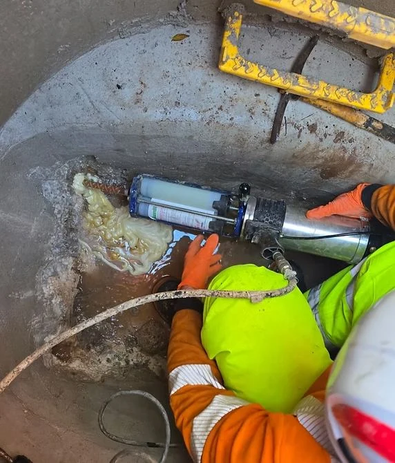 Flux Sewer engineer operating CCTV drain survey equipment in a manhole chamber